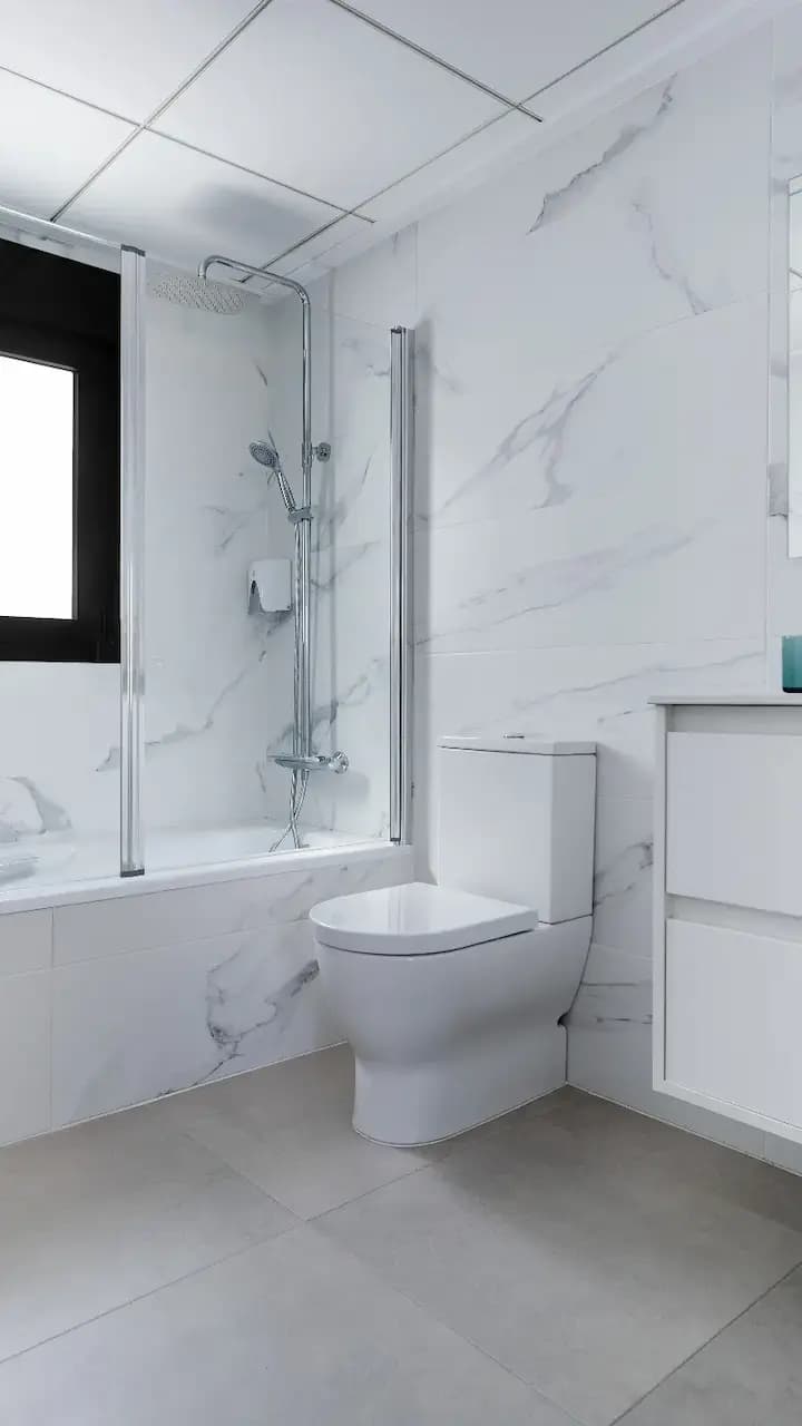 A luxurious bathroom with elegant marble walls and pristine white fixtures.