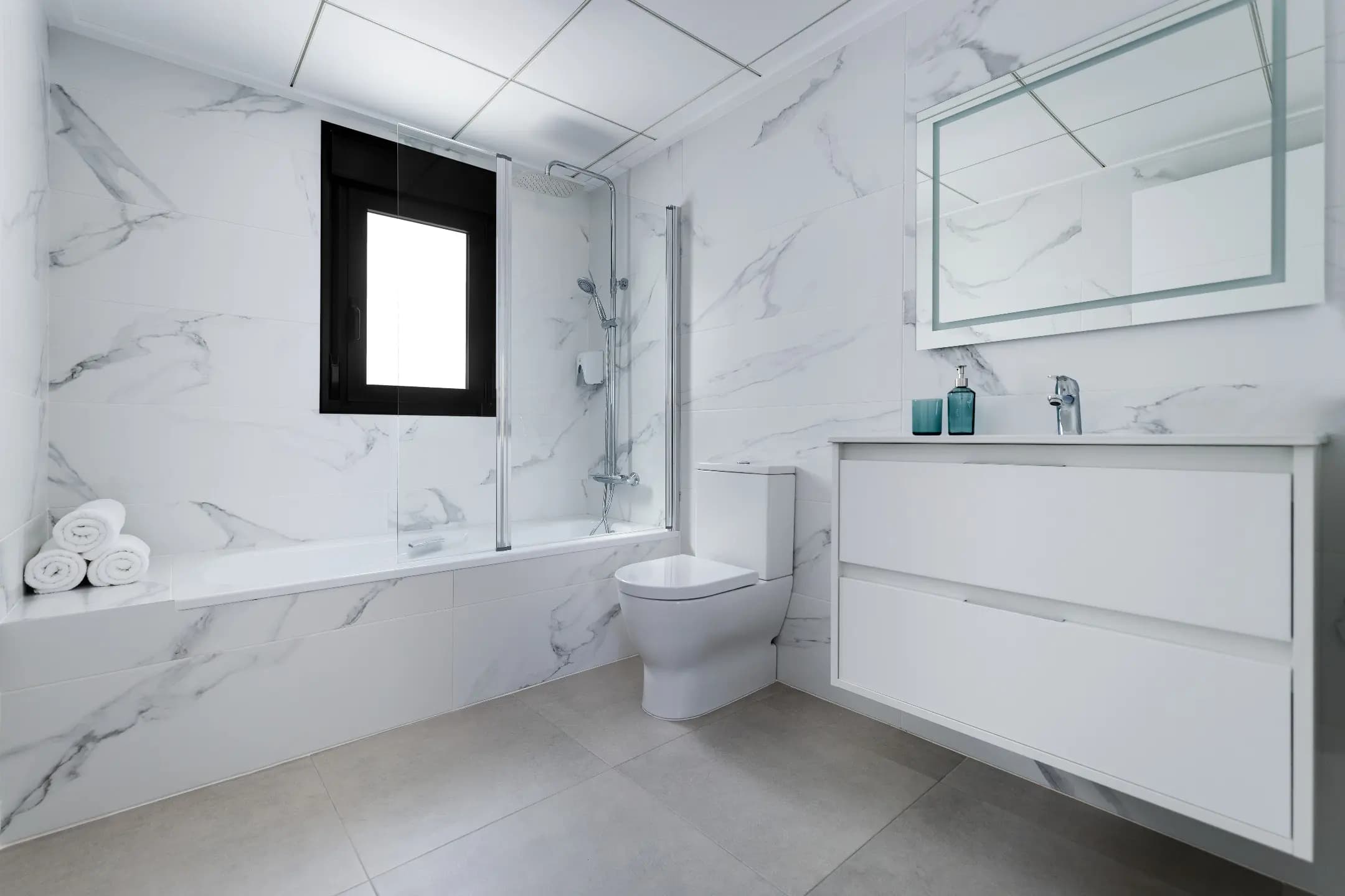 A luxurious bathroom with elegant marble walls and pristine white fixtures.