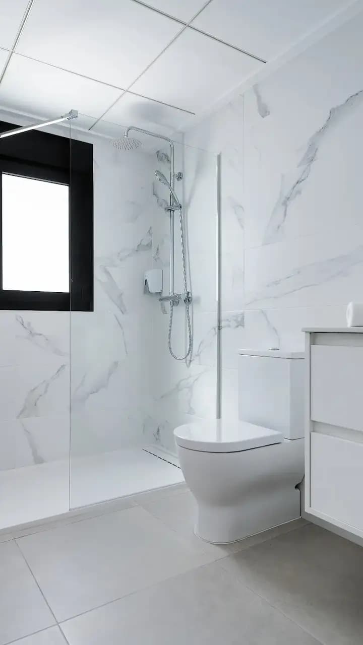 Luxurious white bathroom featuring marble walls and floor.