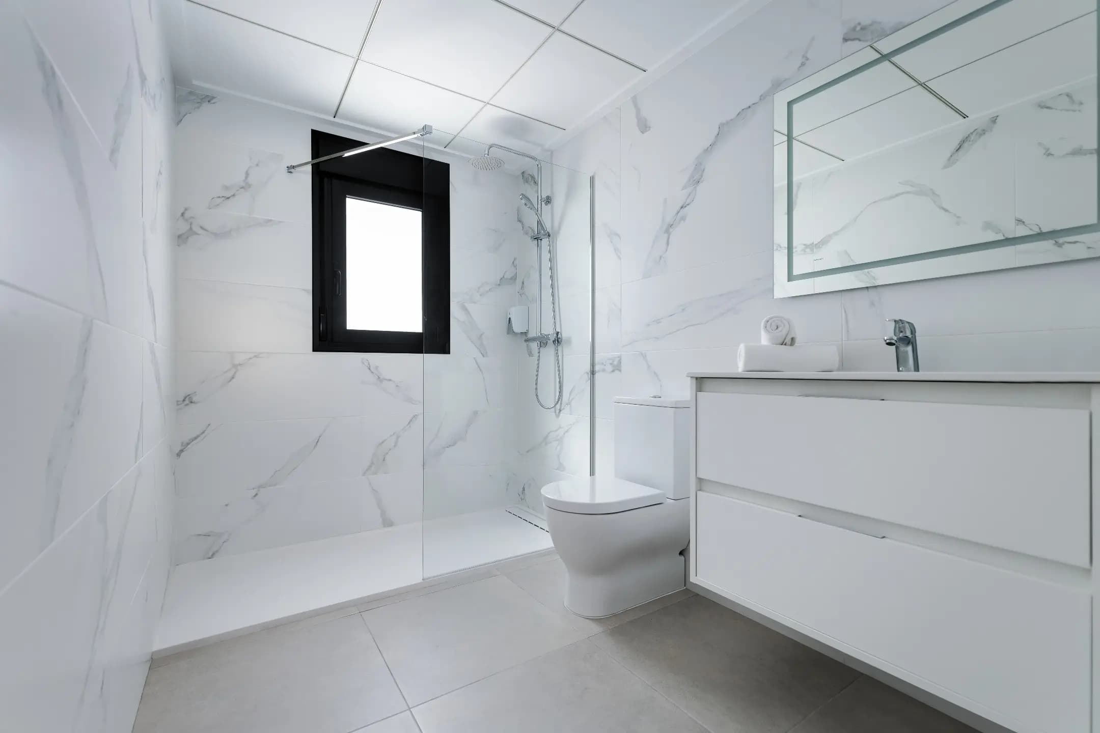 Luxurious white bathroom featuring marble walls and floor.