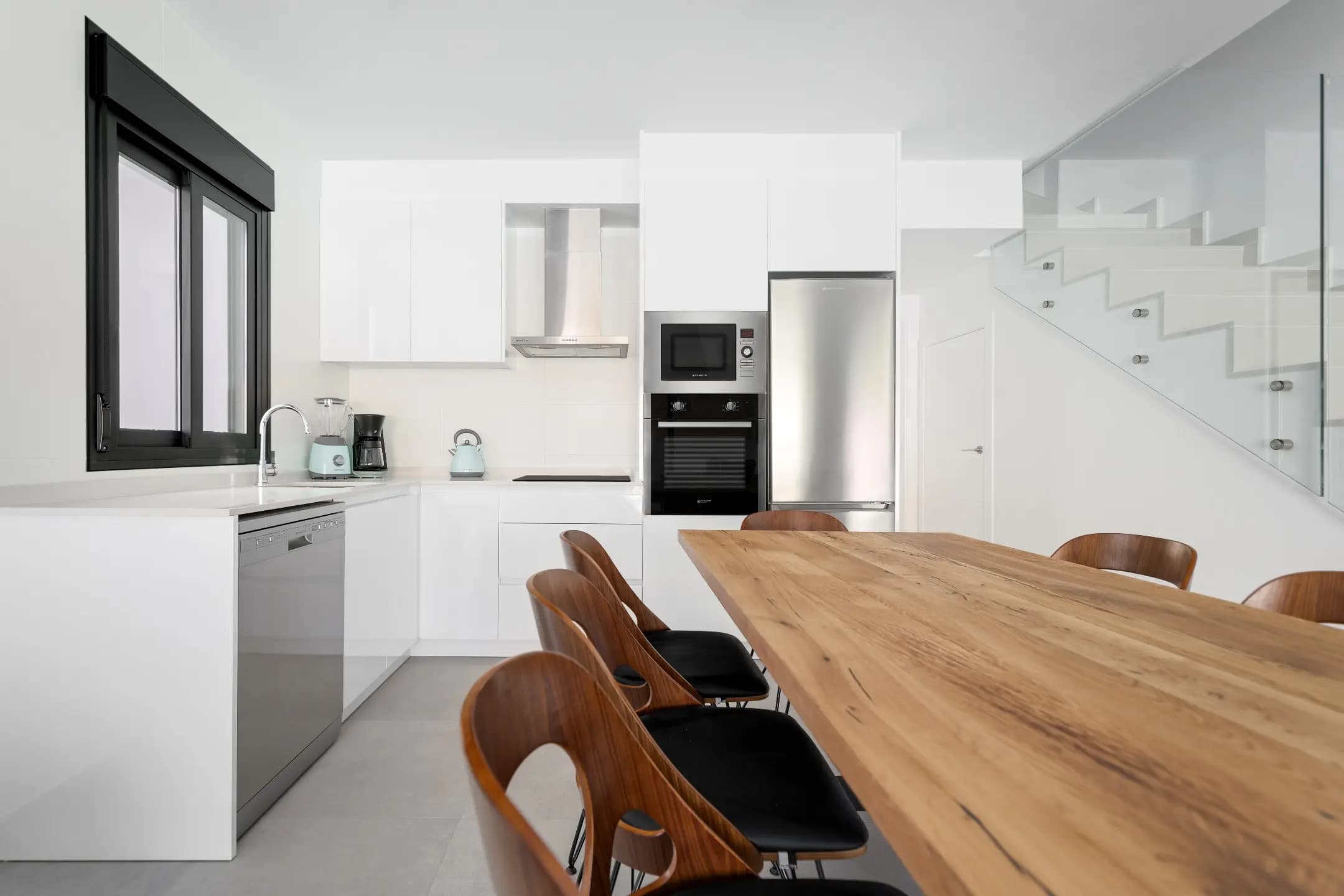 A well-lit kitchen with a wooden table and chairs, creating a cozy and inviting dining area.