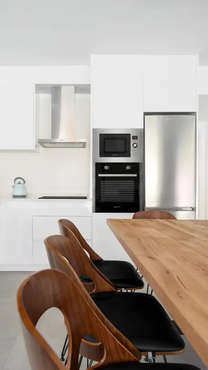 A well-lit kitchen with a wooden table and chairs, creating a cozy and inviting dining area.