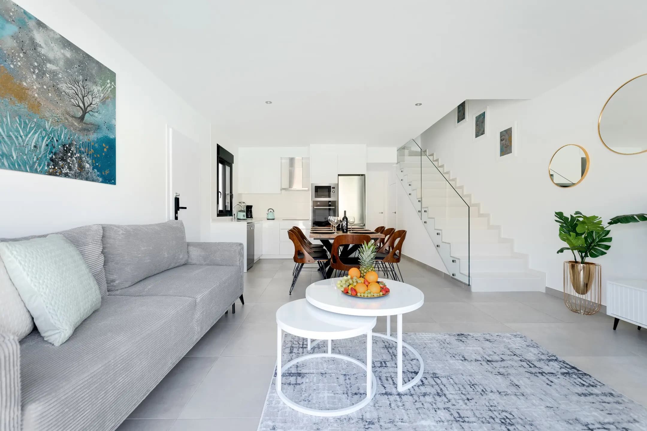 A contemporary living room featuring a white couch and table, creating a sleek and minimalist ambiance.