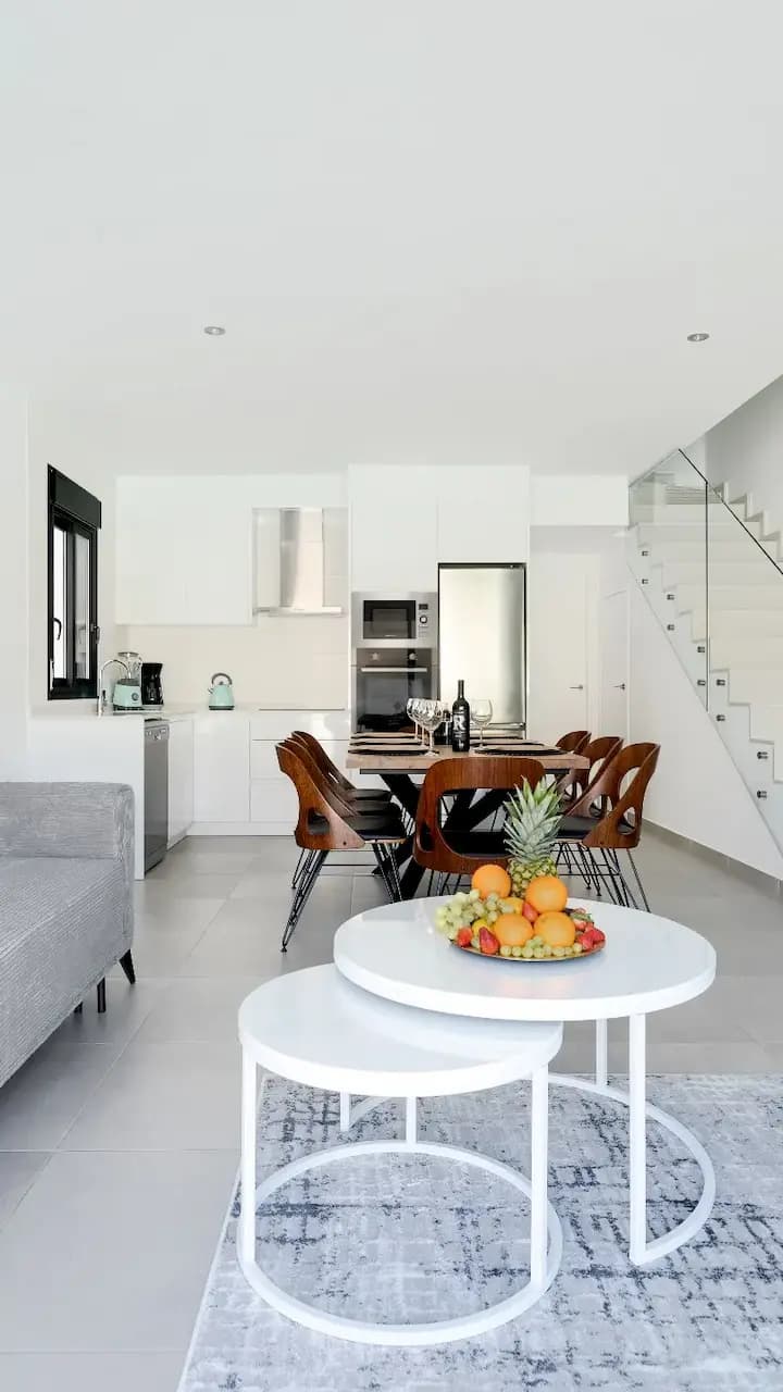 A contemporary living room featuring a white couch and table, creating a sleek and minimalist ambiance.