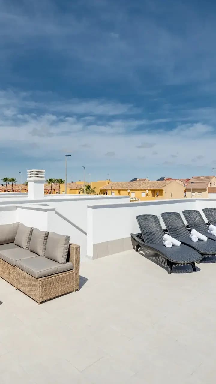 Rooftop patio with lounge chairs and table, perfect for relaxing outdoors.